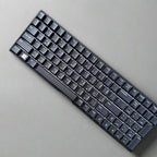 Black keyboard held by a hand against a stone wall background