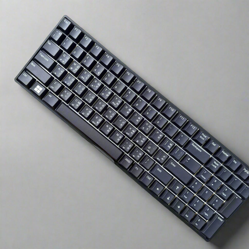 Black keyboard held by a hand against a stone wall background